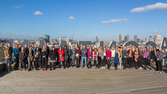 A group of employees on the roof of a building in London with a cityscape including St Pauls in the background